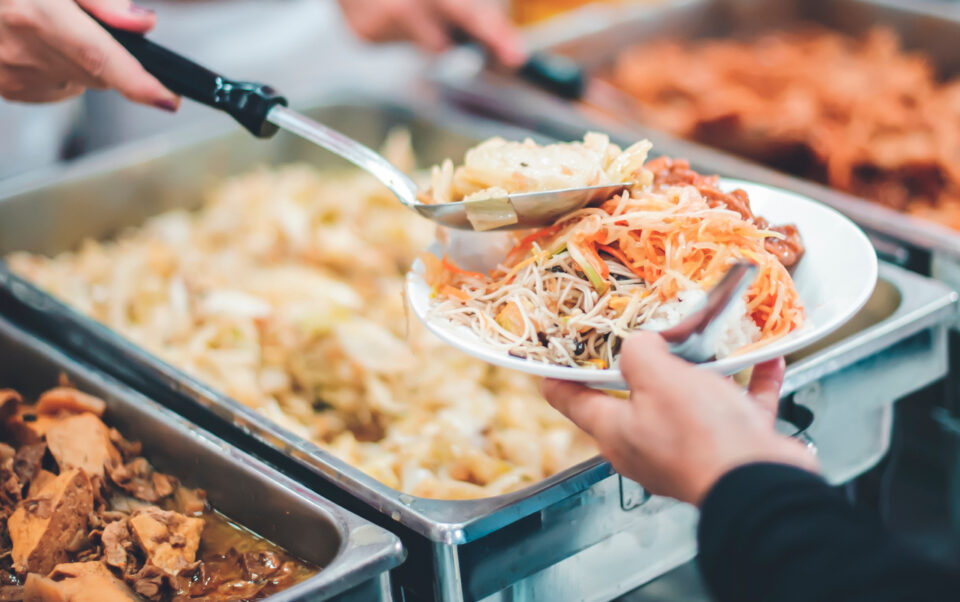 A child being served food from a large metal tray
