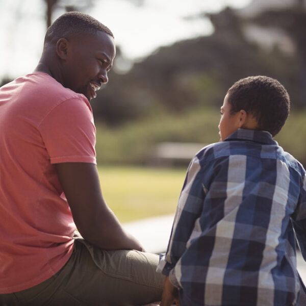 A man and boy talking to each other in a park