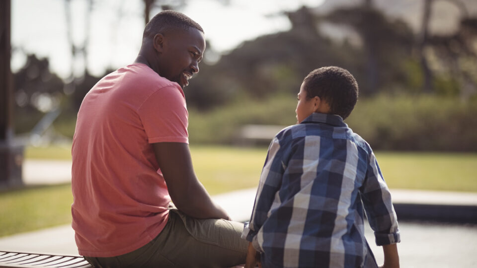 A man and boy talking to each other in a park