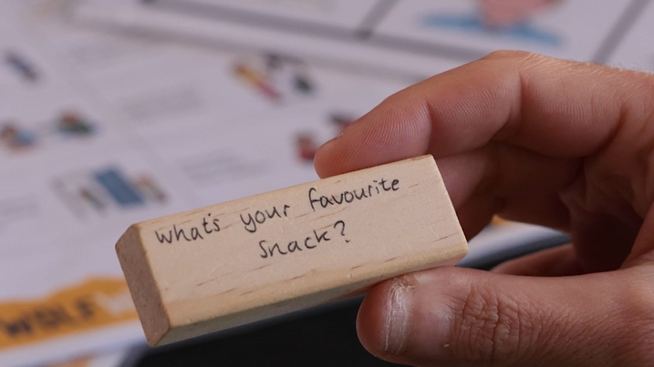 A hand holding a Jenga block with the question: what's your favourite snack?
