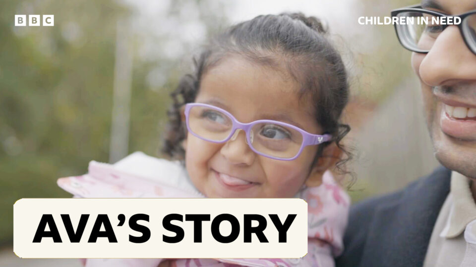 A young girl wearigng purple glasses smiling into the camera