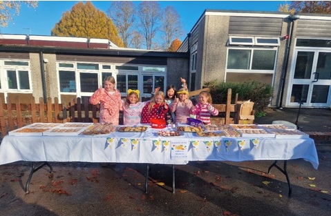 A group of people stood behind a trestle table waving