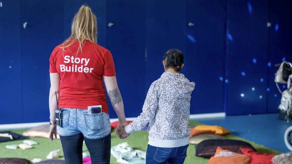 A young person stood holding hands with a project worker