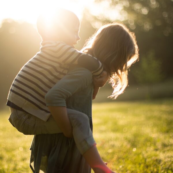 A young girl giving a young boy a piggyback
