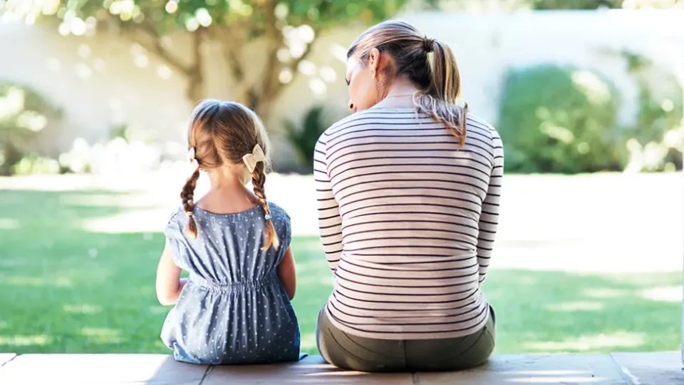 An adult sat outside next to a child