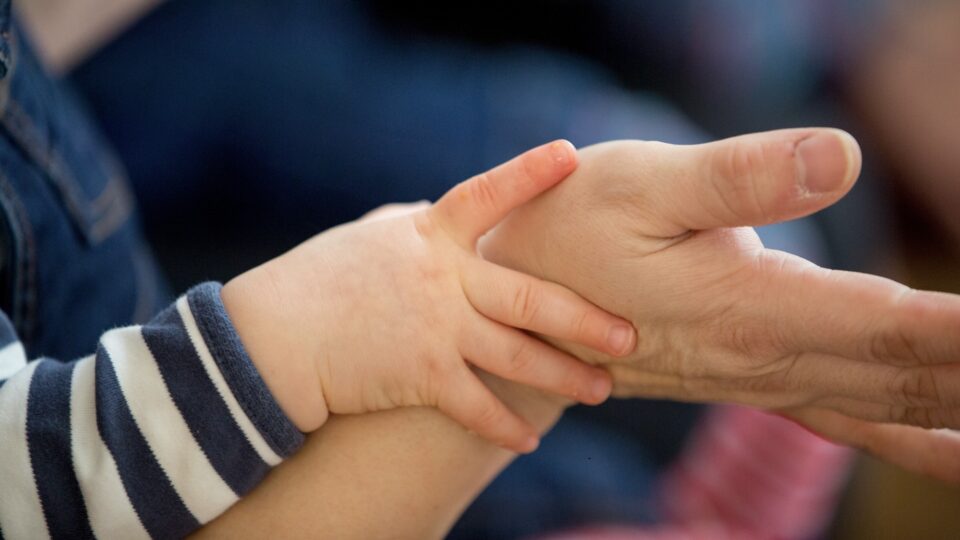 a child holding onto an adult's wrist/hand