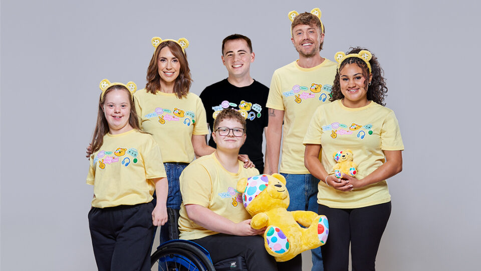 Four young people in a group with Children in Need presenters Alex and Roman